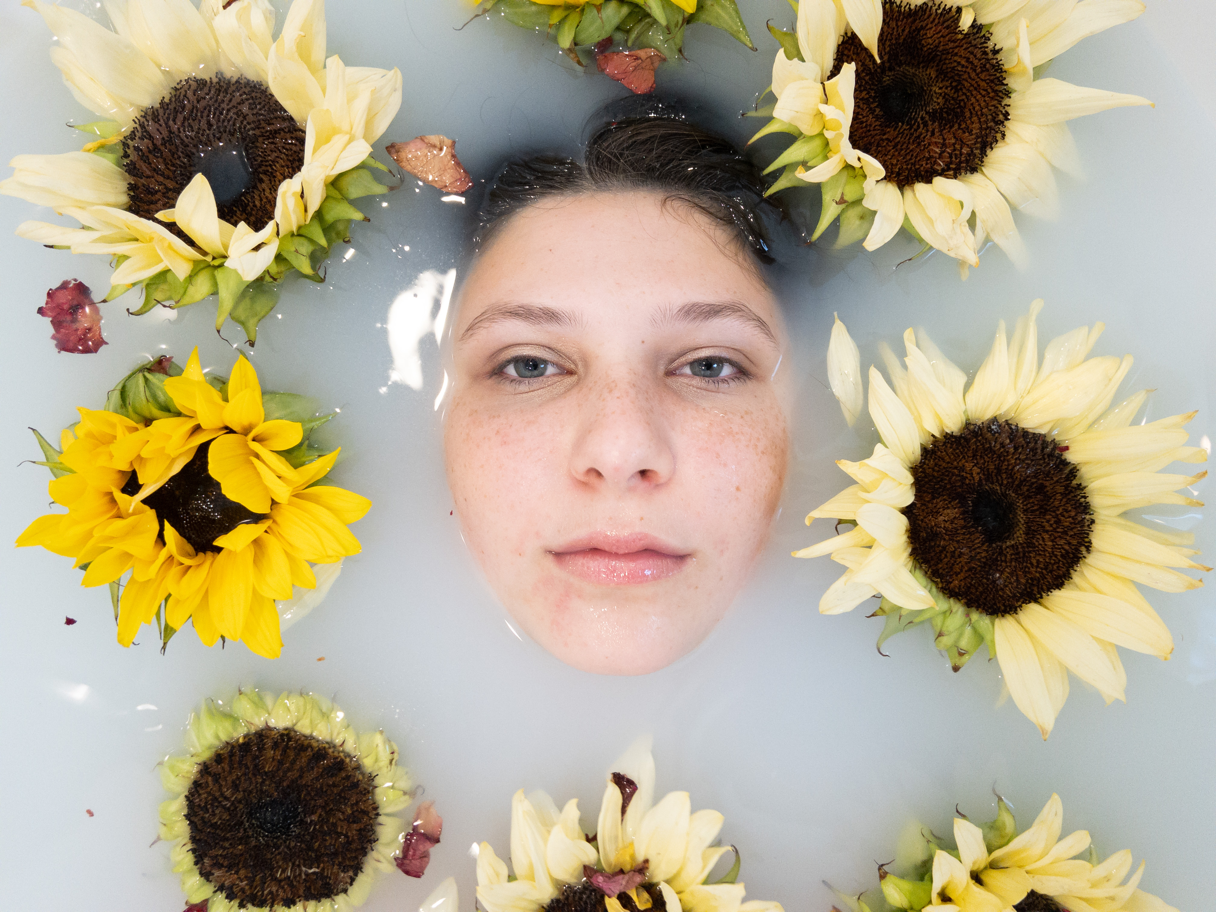Editorial Shot - Girl Lying in Bathtub Filled with Water, Surrounded by Flowers 